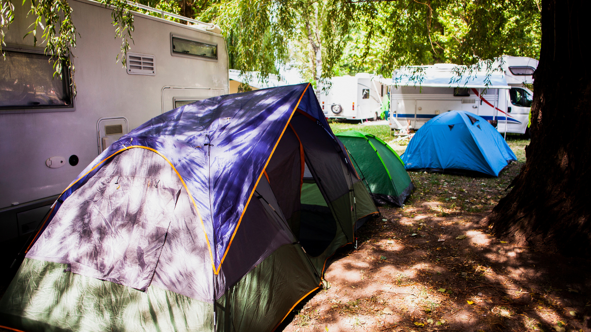 Campeggio moderno con tende e camper in un ambiente naturale durante il periodo di alta occupazione
