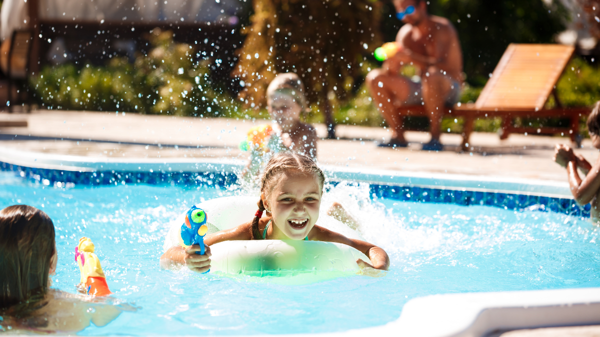 Famiglie che si godono le vacanze estive in un villaggio turistico con piscina e strutture ricreative durante l'alta stagione